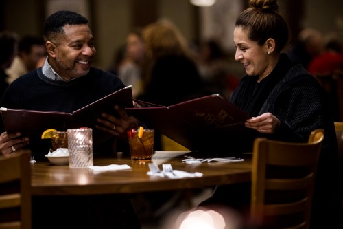 A couple with menus at a table inside Roxy Supper Club