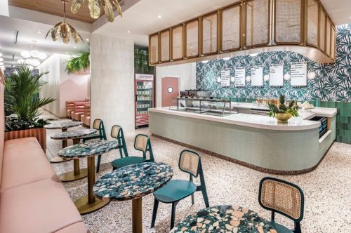 Interior of an ice cream shop with jewel-tone tables and chairs and an ice cream bar.