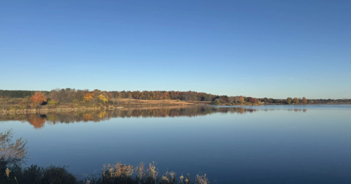 Glassy Shabbona Lake in Illinois under blue skies on an autumn day.
