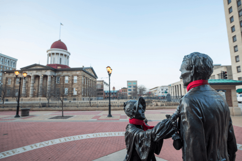 The Old Illinois State Capitol building in the background with statues of Mary Todd Lincoln and Abe Lincoln in the foreground.