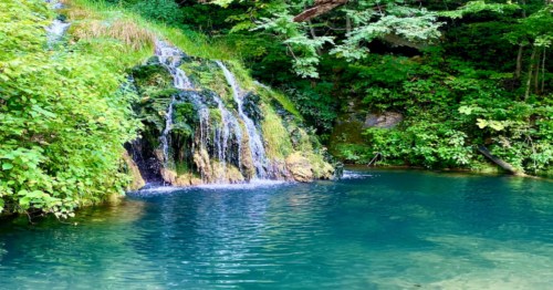 Tiered waterfall flows into blue pool of water at a campsite in VA.