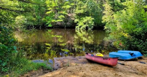 Views of kayaks on a riverbank at Suncook River Camp, a waterfront campground in NH.