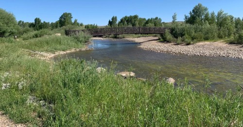 The Bear River lazily flows under a long bridge on a summer day at Bear River State Park in Evanston, Wyoming.