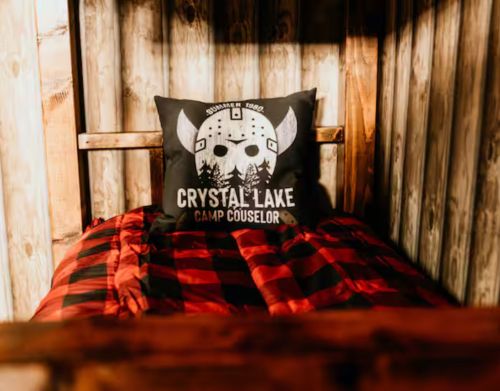 A bunkbed with a red duvet and a pillow with a scary character on it.
