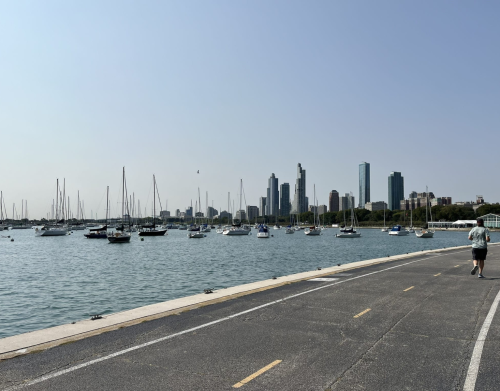 A man is running on a concrete path next to a marina.