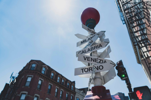 A sign post in Boston's North End neighborhood. The sign displays multiple arrows with names of Italian cities written on them.
