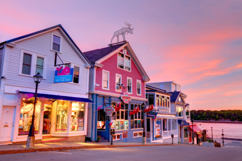 A sunset view of a quiet street lined with buildings in Bar Harbor, Maine.