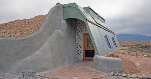 The exterior of a uniquely-shaped Earthship Airbnb in New Mexico.