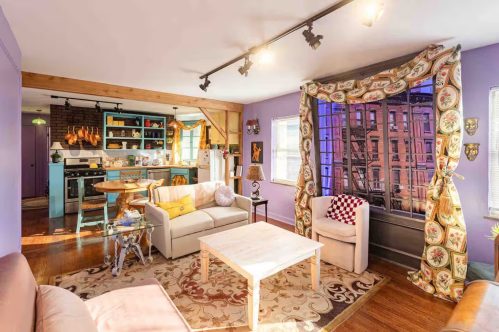 An Airbnb is decorated to look like the apartment in Friends, with purple walls and an open-concept living space and windows overlooking Greenwich Village.