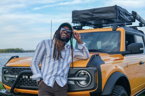 Man smiling in front of 4x4 vehicle with roof top tent