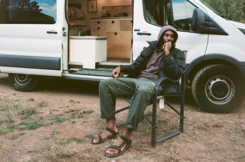 Man sitting in camp chair outside of a van