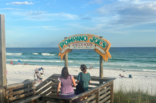 Wooden staircase under a restaurant sign leading to the beach in Florida