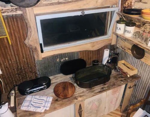 A rustic cowboy kitchen with a sink and hotplate.