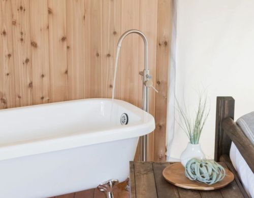 A white bathtub next to a wooden wall.