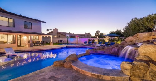 a large pool and waterfall in the backyard of a large arizona airbnb