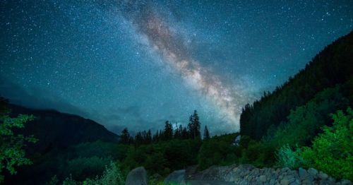 Night sky filled with stars and the Milky Way galaxy, with a lush forest and mountains, at Pearrygin Lake State Park, a stargazing spot in WA.