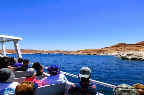 Views of passengers on a boat looking at the red rock cliffs along Lake Powell on the ultimate summer adventure in Arizona.