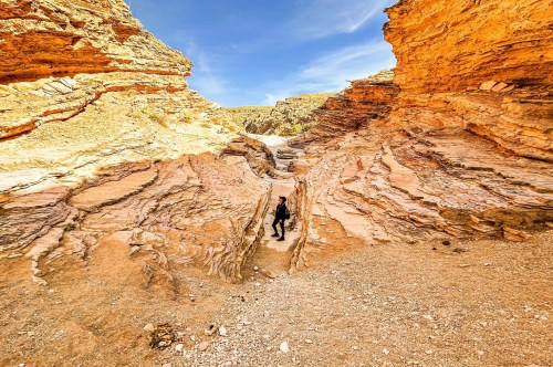 A solo hiker standing between the limestone walls of a slot canyon along a hidden gem trail at Big Bend National Park in Texas