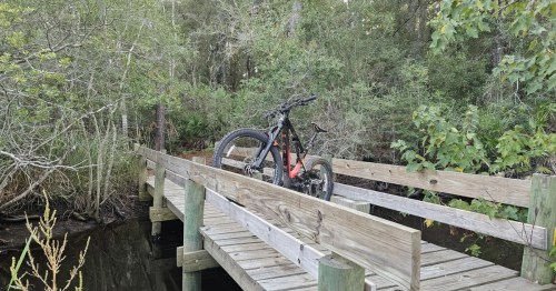 a mountain bike resting on the railing of a boardwalk trail in mississippi