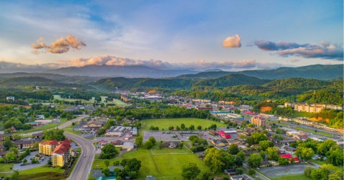 Aerial view of Pigeon Forge, TN in the summer showcasing mountains, green rolling hills, and attractions