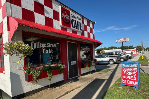 A shoebox-size restaurant is decorated with a cherry red checkerboard and colorful flower planters.
