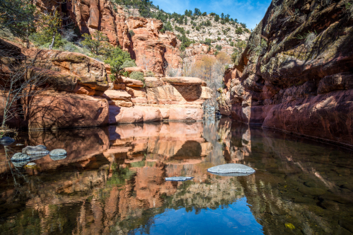 a clear swimming hole surrounded by red rocks in arizona
