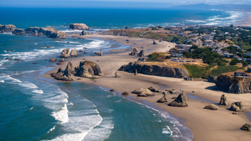 A panoramic view of a scenic coastal landscape featuring rugged rock formations, sandy beaches, and ocean waves in Bandon, OR.