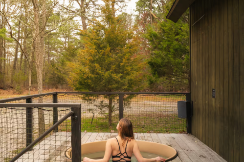 A woman sits in a hot tub on the porch of the Lokal Chalet Airbnb property in Egg Harbor City, New Jersey.