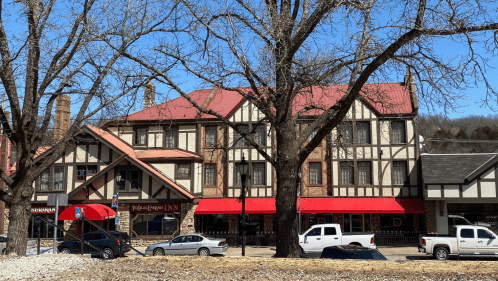A historic hotel features Tudor Revival architecture with a red roof and sidewalk canopy