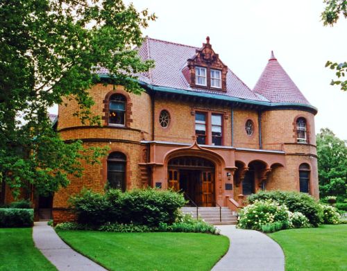 A large Châteauesque-style home with a well-manicured garden.