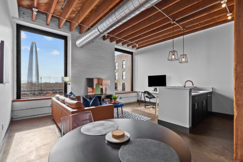 A cozy industrial loft has large windows with views of the Gateway Arch and downtown St. Louis