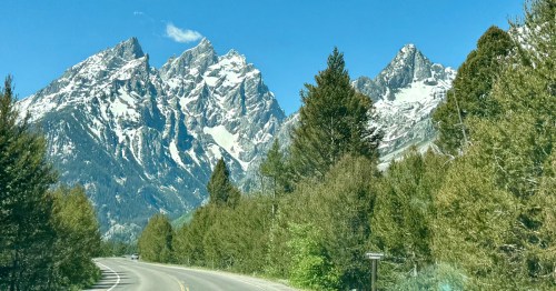 A two-lane highway leads toward the base of the Teton Mountains inside Grand Teton National Park.