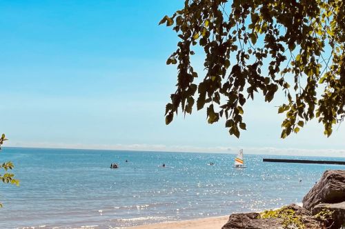 A beach with a sailboat in the background.