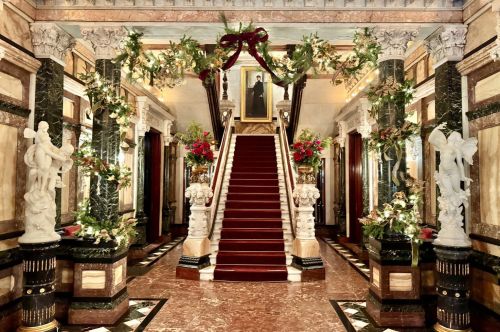 View of the entry to a Gilded Age mansion that is decorated for the winter holidays.