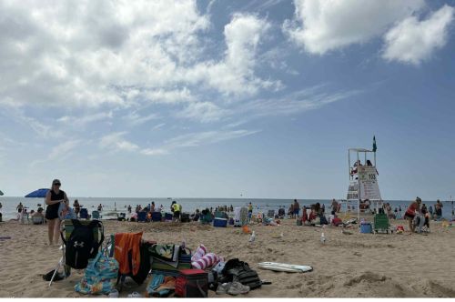 View of a busy beach with a lifeguard stand in the background.