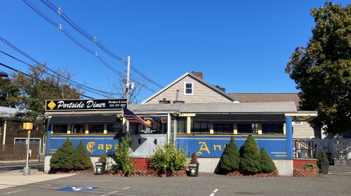 The exterior of the Portside Diner in Danvers, Massachusetts. An American flag flies outside of the old dining car.