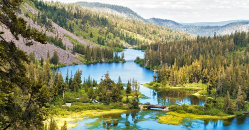 Large, bright blue lakes are surrounded by tree-covered mountains near Mammoth Lakes, California.