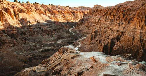 A woman hikes down a staircase into a deep canyon at Nevada's Cathedral Gorge State Park.