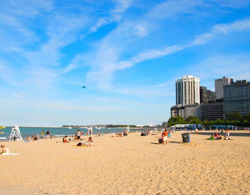 People are spread out and sitting on the beach with buildings in the background.
