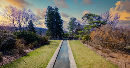A beautiful reflecting pond, grassy areas, and colorful trees and bushes at the New Jersey Botanical Gardens.