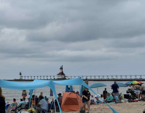 Two red and white lighthouses in the background of a beachfront.