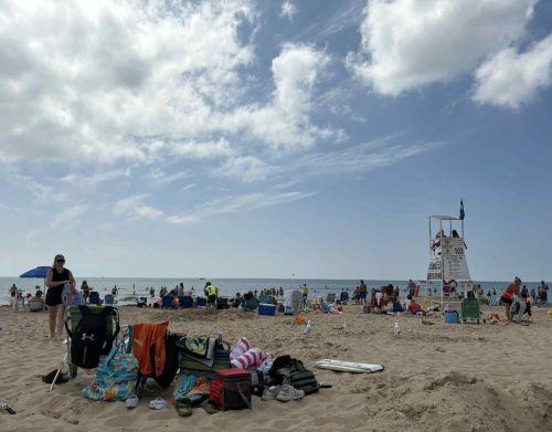 View of a busy beach with a lifeguard stand in the background.