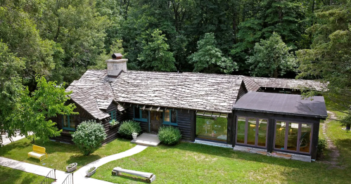 Log cabin house on a grassy hill surrounded by trees