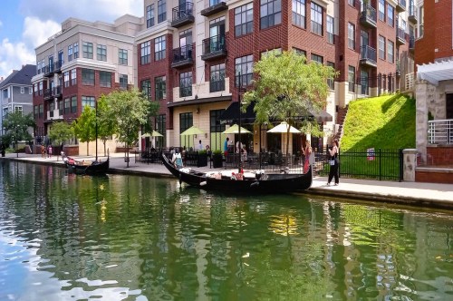 Two gondolas docked in front of several brick buildings along a scenic canal inside White River State Park in Indianapolis.