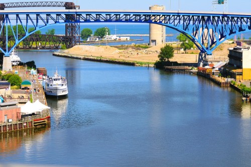 Expansive views of the Cuyahoga River in Cleveland, Ohio, surrounded by several bridges, a pier, and a docked cruise boat.