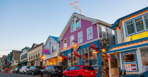A busy street lined with shops, vehicles, and people on a summer day in Bar Harbor, Maine.