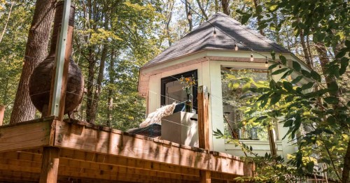 A white gazebo treehouse with a wooden deck.