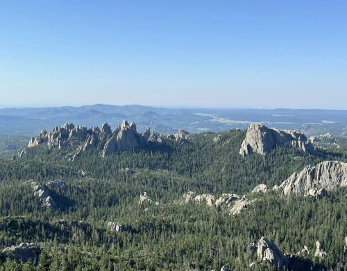 Wide view of rock formations, hills, and a forest.