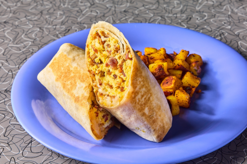A blue plate holds a breakfast burrito (cut in half) and home fries from The Friendly Toast restaurant.