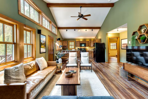 interior of a cabin with green walls, ceiling beams, and cozy furniture